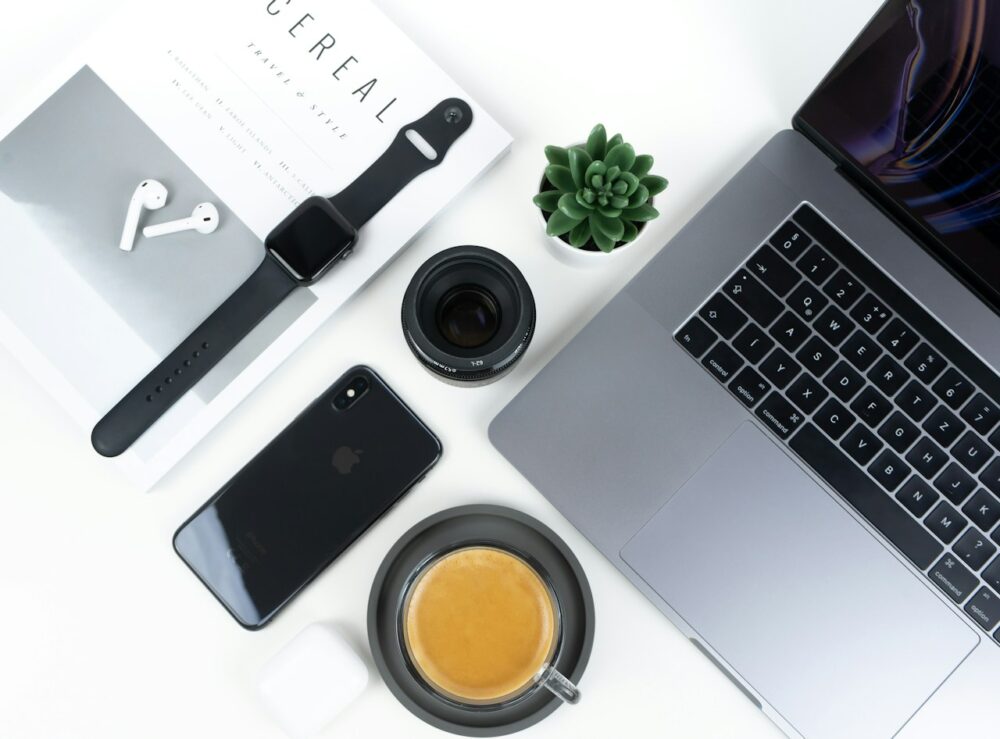 Modern tech gadgets and coffee arranged on a white desk.