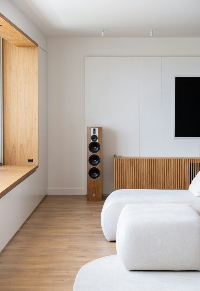 A tall floor speaker sits beside a media unit.