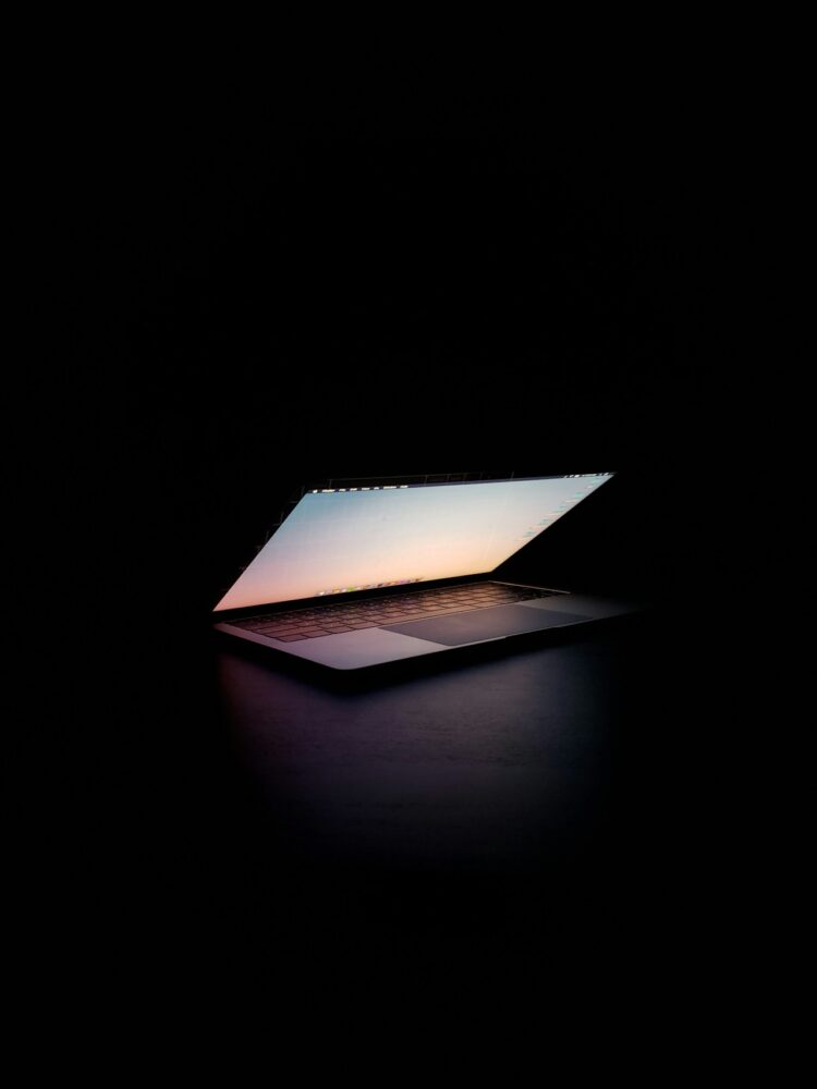 A modern silver laptop open on a dark surface.